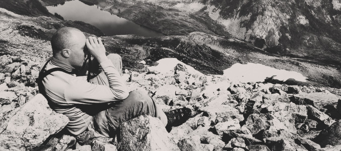 Photo of man using binocs to glass for bears on hunt near Alaska.